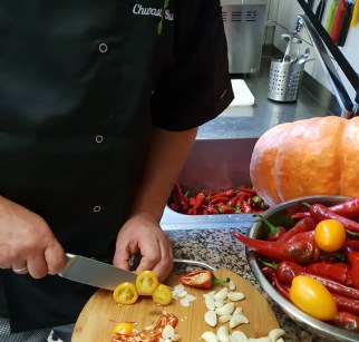 Zdjęcie przedstawia szefa kuchni krojącego ostre papryczki