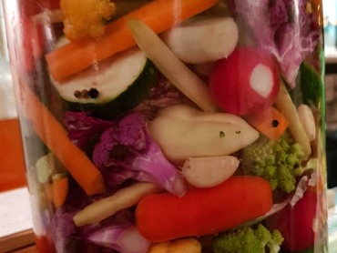 Zdjęcie przedstawia słój wypełniony kiszonymi warzywami